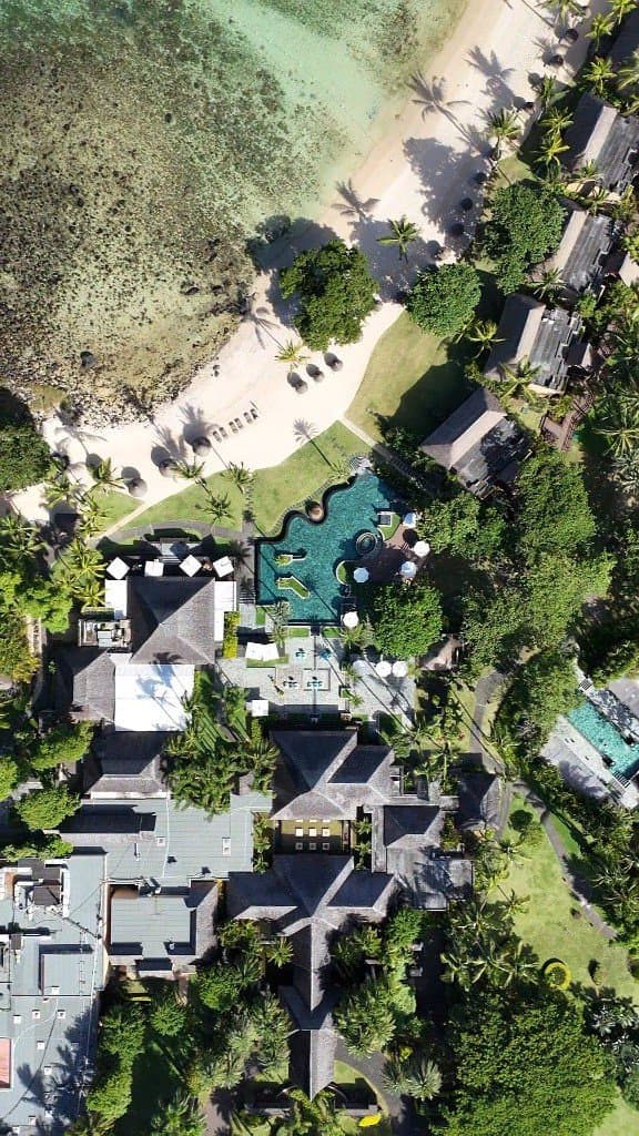 Vue drone d’un resort tropical, plage, palmiers et piscine au milieu des jardins