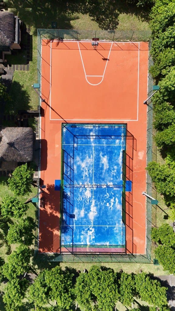 Vue aérienne verticale d’un terrain de basketball rouge et d’un court de padel bleu